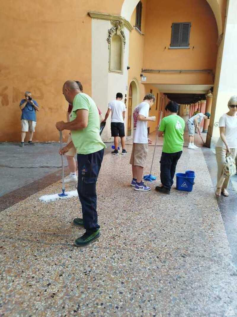 Operatori Ambienta e allievi dell'Enrico Fermi impegnati nella pulizia dei Portici di Bologna
